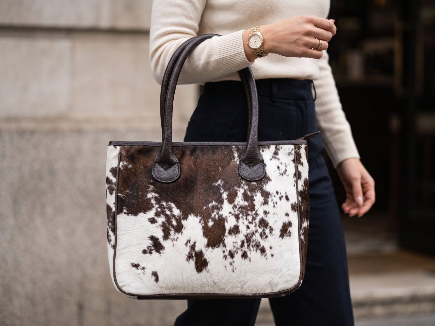 Woman carrying the Hashmeers pure leather hair-on cowhide handbag in brown and white