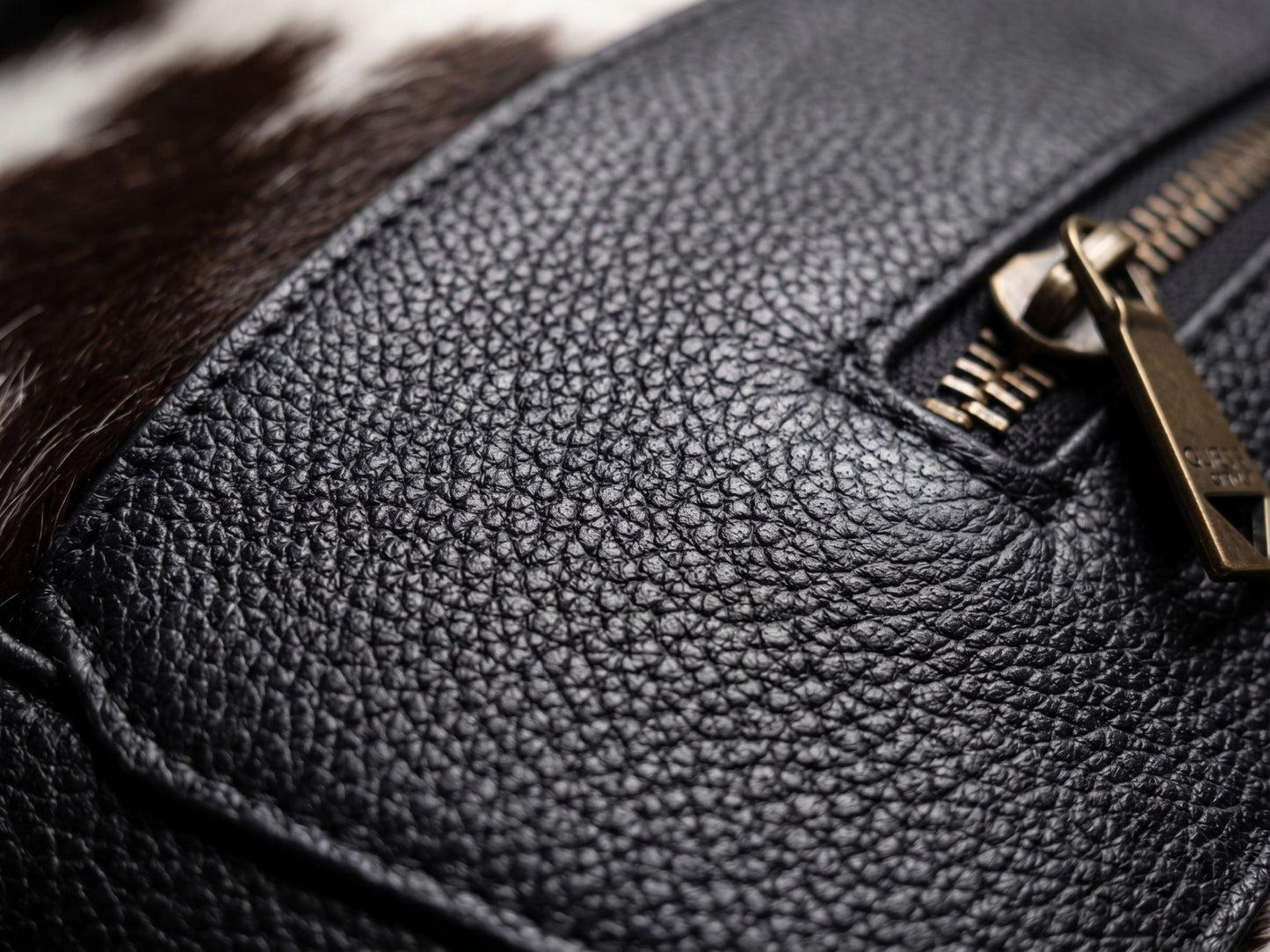 Close-up of the black grain leather trim on the Hashmeers hair-on cowhide travel bag